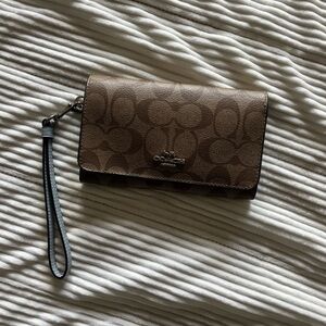 Classic tan Coach wristlet with light blue accents